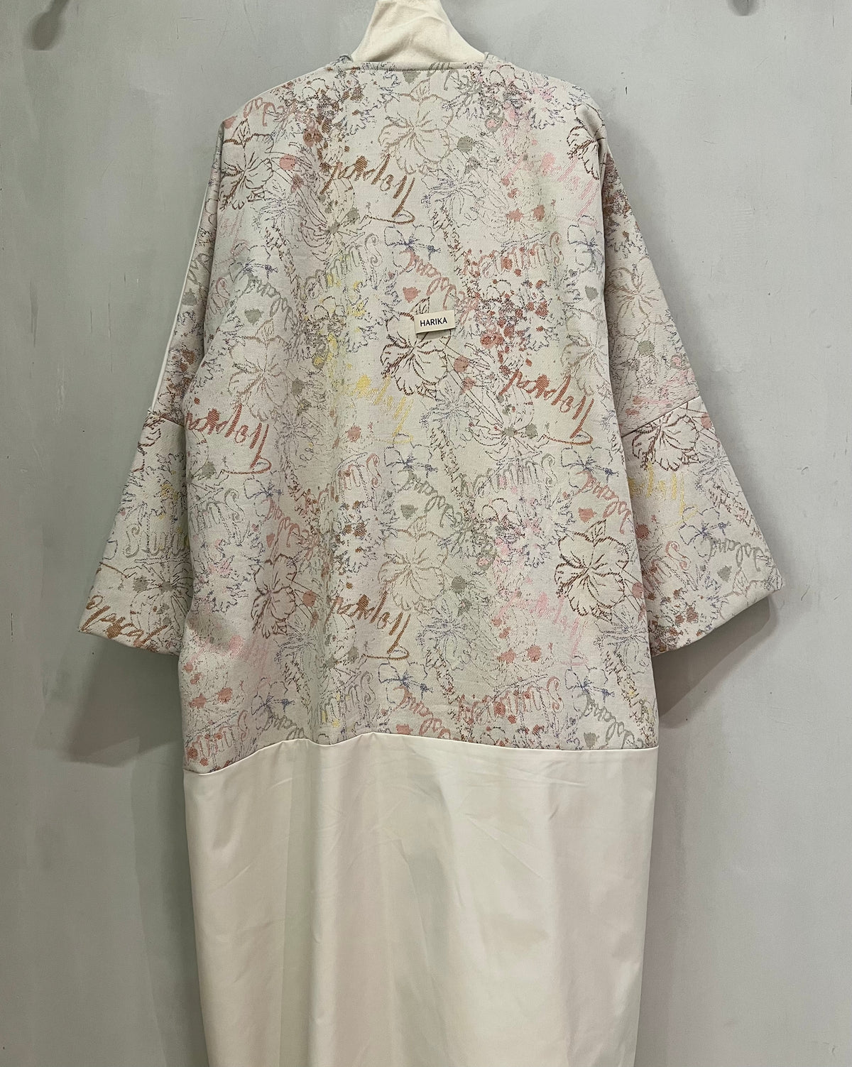 Abaya- stunning ivory abaya, featuring a sophisticated open-front design and beautifully detailed floral-patterned cuffs in soft blush pink and muted beige tones
