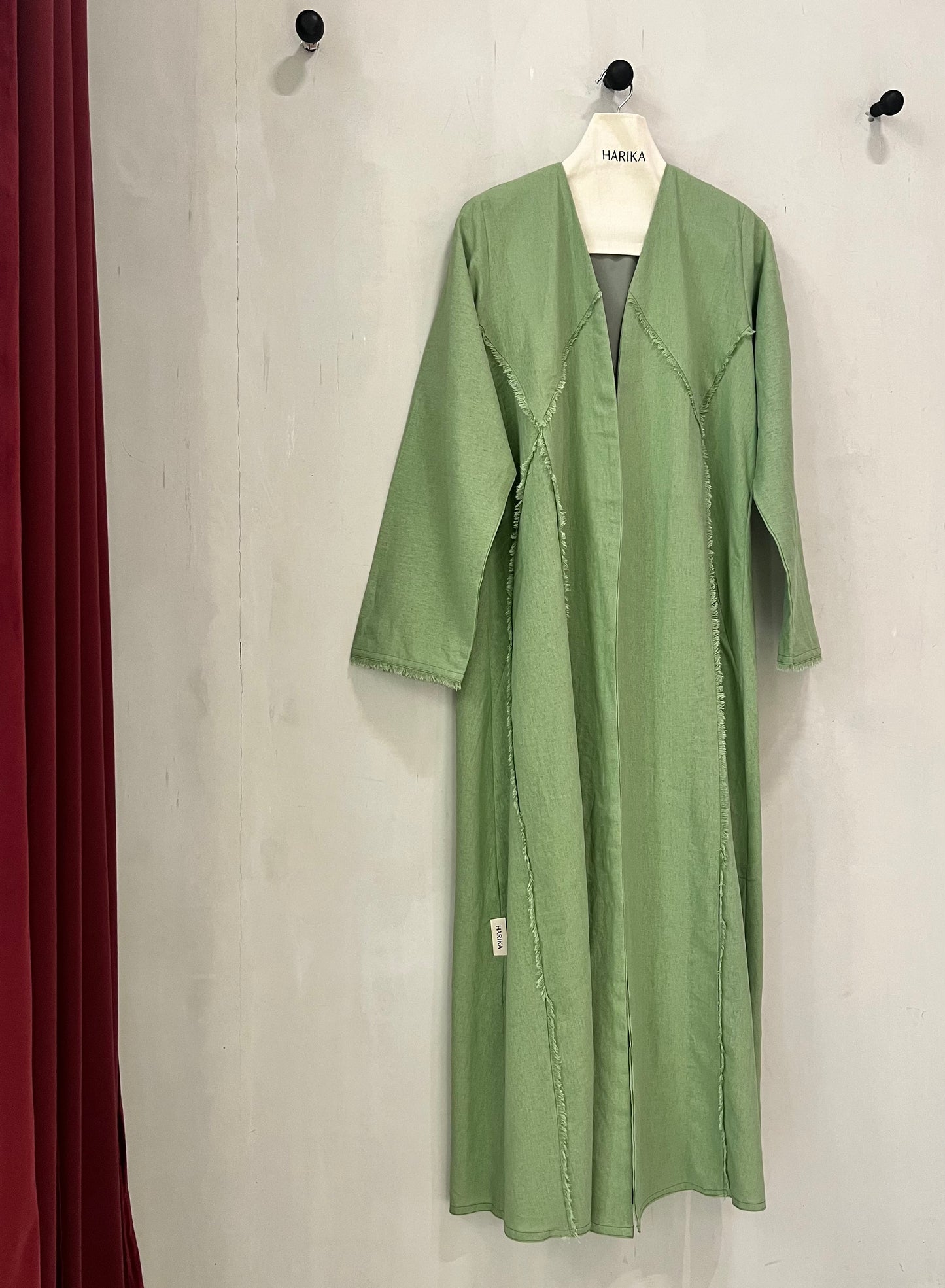 Abaya - Sage green features a contemporary minimalist design with artistic raw-edge detailing